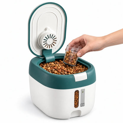 Conteneur croquette chat - Stova : 5 kg Vert Eucalyptus ouvert, avec une main tenant un verre gradué rempli de croquettes - AstuceChat